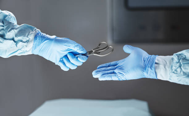 Cropped shot of an unrecognizable surgeon passing his colleague a pair of scissors
